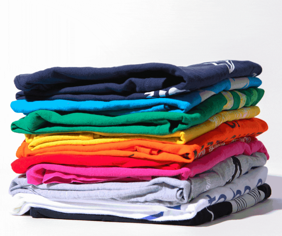 A stack of colorful t-shirts with confetti falling over them