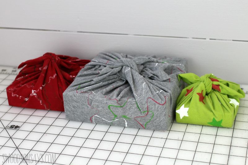 Three rectangular gifts wrapped artfully with uypcycled t-shirts.
