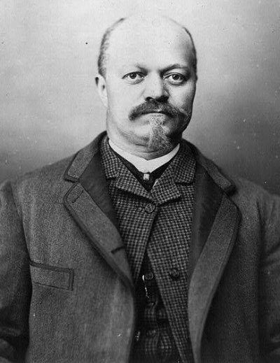 A black and white 19th century photograph of a Black businessman wearing a suit