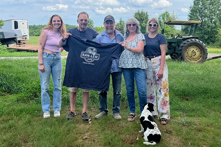 Randy Lewis and Eric Henry holding up a sample of his shirt with the TS Designs Marketing Team, and Lovely the pup.