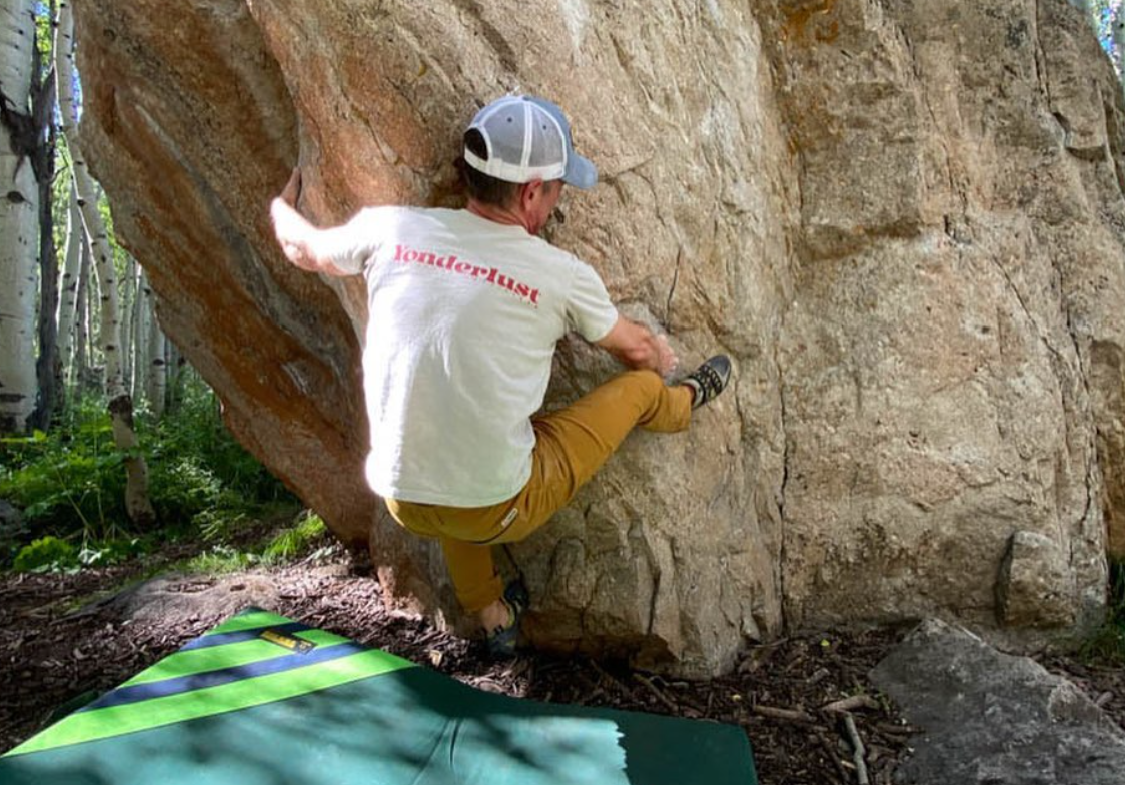 Image of Yonderlust owner Kit Linton climbing a rock