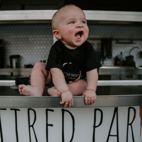 Adorable 18 month baby of the two tired parents, sitting on the food truck.
