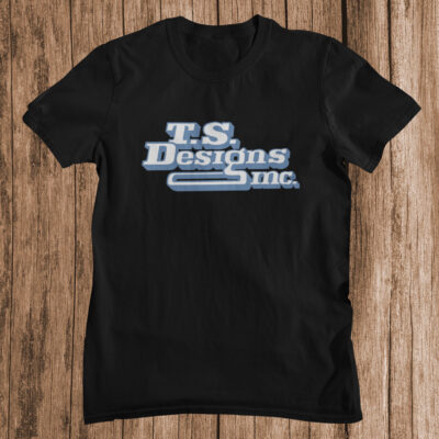 Image of a black t-shirt printed with our retro TS Designs logo, against a wood background
